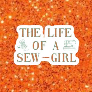 May include: A white sticker with the text "THE LIFE OF A SEW - GIRL" in a mix of teal and orange lettering. The design includes a spool of thread, a sewing machine, and a needle. The background is orange glitter.