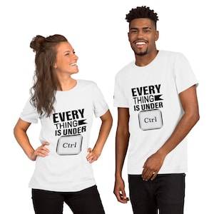Pode incluir: Duas t-shirts brancas de manga curta com o texto preto "EVERY THING IS UNDER" sobre um gráfico de uma tecla "Ctrl" de teclado de computador. O design está centrado no peito de cada t-shirt, que possui uma gola redonda.