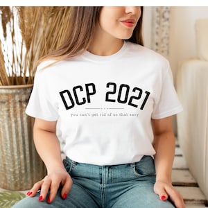 May include: White t-shirt with black text that reads "DCP 2021" and "you can't get rid of us that easy".