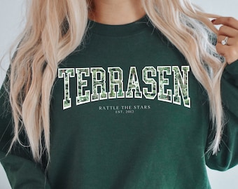 May include: A dark green sweatshirt with a white graphic print that says "TERRASEN" in a collegiate font. The graphic also includes the text "RATTLE THE STARS EST. 2012".
