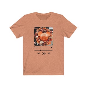 May include: A heather brown t-shirt with a graphic of a Mickey Mouse pumpkin on a wreath. The graphic is in a social media post format with the text "Boo to You! Mickey's Not So Scary Halloween Party" and a play button.