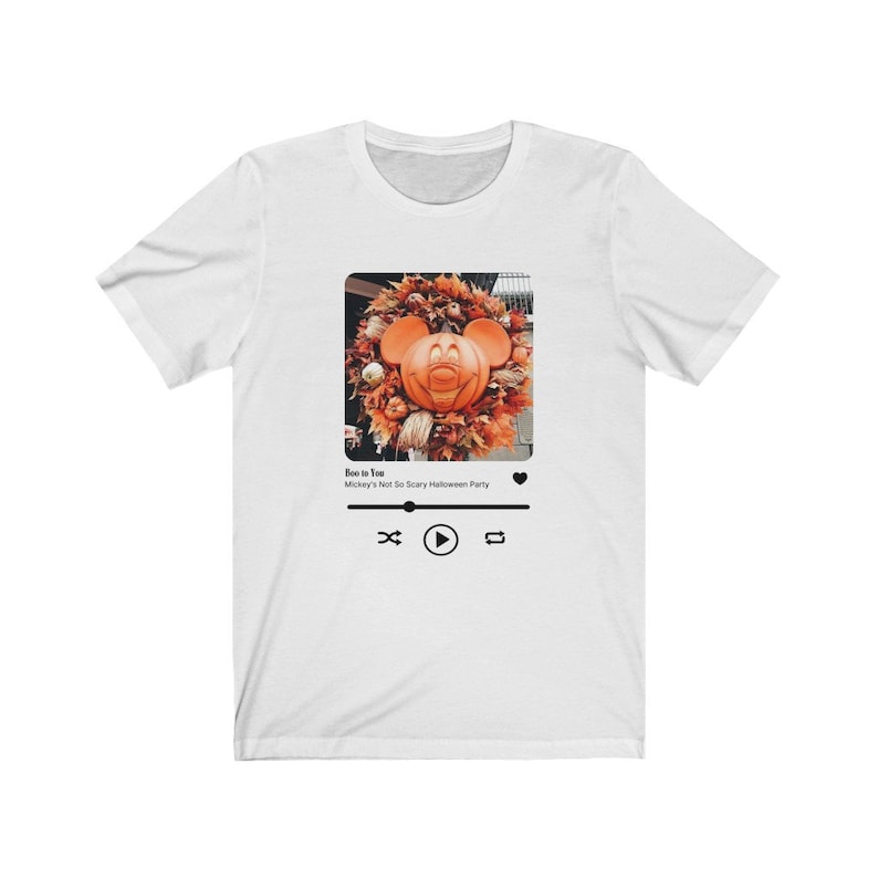 May include: White t-shirt with a graphic of a Mickey Mouse pumpkin head in a wreath. The graphic is in a black frame with a play button and a heart icon. The text below the graphic reads "Boo to You" and "Mickey's Not So Scary Halloween Party."