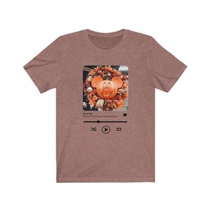 May include: A brown t-shirt with a graphic of a Mickey Mouse pumpkin head in a fall wreath. The graphic is in a social media post format with the text "Boo to You! Mickey's Not So Scary Halloween Party" and play, pause, and repeat buttons.