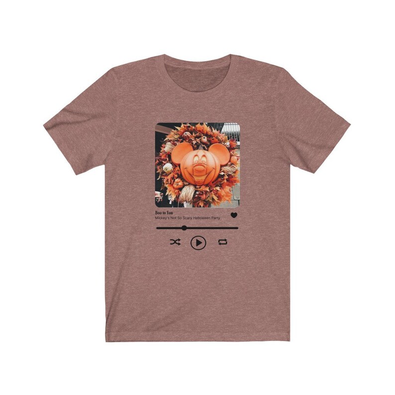 May include: A brown t-shirt with a graphic of a Mickey Mouse pumpkin head in a fall wreath. The graphic is in a social media post format with the text "Boo to You! Mickey's Not So Scary Halloween Party" and play, pause, and repeat buttons.