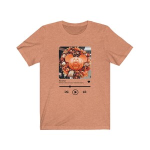 May include: A heather brown t-shirt with a graphic of a Mickey Mouse pumpkin on a wreath. The graphic is in a social media post format with the text "Boo to You! Mickey's Not So Scary Halloween Party" and a play button.