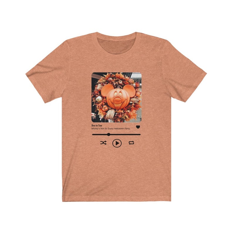 May include: A heather brown t-shirt with a graphic of a Mickey Mouse pumpkin on a wreath. The graphic is in a social media post format with the text "Boo to You! Mickey's Not So Scary Halloween Party" and a play button.