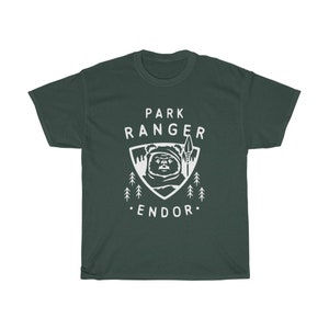 May include: A dark green t-shirt with a white graphic of a creature from the Star Wars movie, 'Return of the Jedi'. The graphic includes the text 'Park Ranger Endor'.
