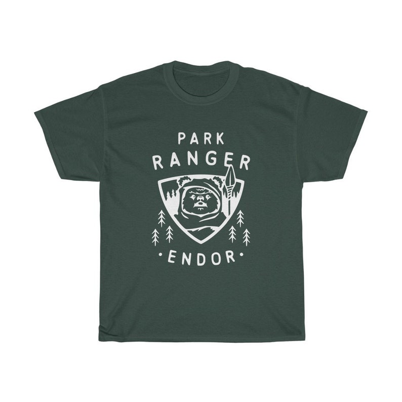 May include: A dark green t-shirt with a white graphic of a creature from the Star Wars movie, 'Return of the Jedi'. The graphic includes the text 'Park Ranger Endor'.