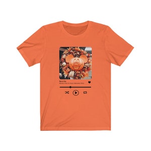 May include: Orange t-shirt with a graphic of a Mickey Mouse pumpkin on a music player screen. The text on the screen reads "Boo to You" and "Mickey's Not So Scary Halloween Party".