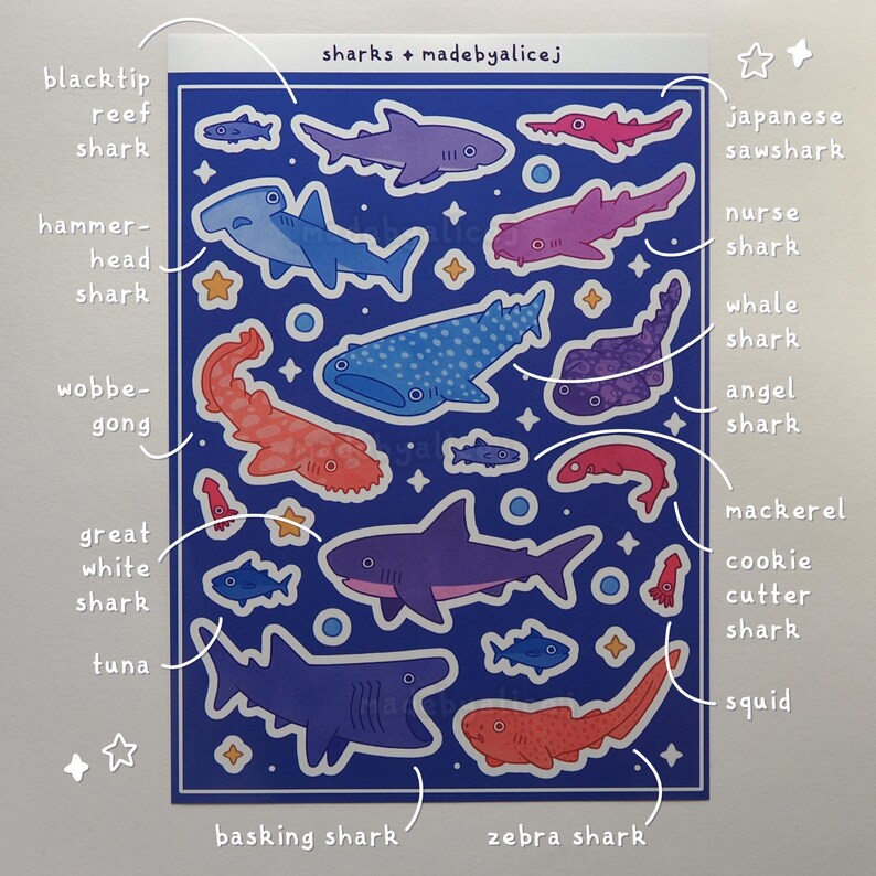 May include: A sticker sheet featuring various shark illustrations in shades of blue, purple, red, and orange. The sheet includes the text "sharks + madebyalicej" and labels for each shark type, such as "hammerhead shark" and "whale shark".