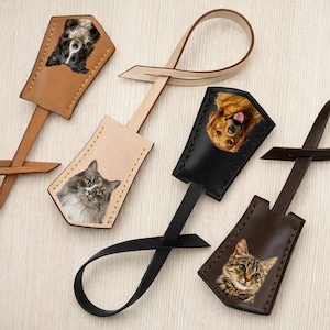 May include: Leather luggage tags featuring portraits of cats and dogs. The tags are in various colors, including tan, black, and brown. Each tag has a loop for attachment and a stitched border. The pet portraits are detailed and realistic.