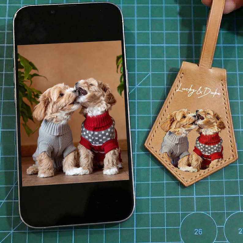 May include: A smartphone displays a photo of two puppies wearing sweaters, one gray and one red. A leather tag with the text "Lucky & Duke" features the same image of the puppies.