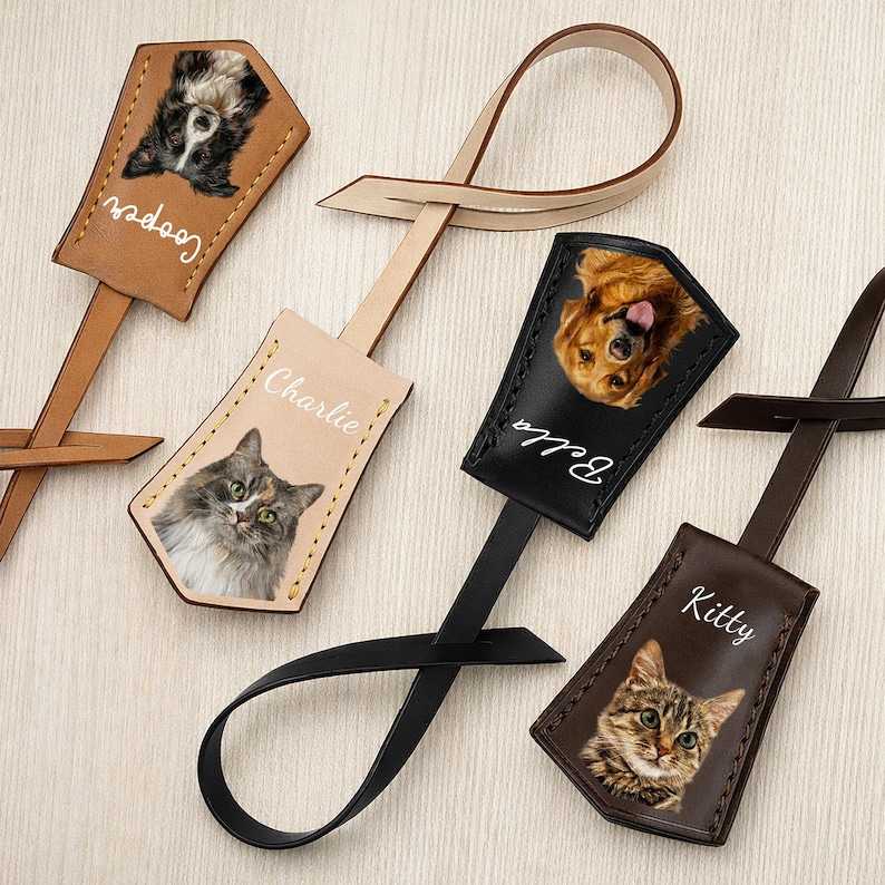 May include: Leather pet luggage tags featuring photos of dogs and cats. Each tag has a different pet's name in white script. The tags are in various colors, including brown, black, and tan, with a loop for attaching to luggage.