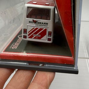 May include: A white and red Bus Eireann Expressway model bus in a clear display case. The rear of the bus features the text "Bus Eireann Expressway" and the license plate "93-D-19590". The model is displayed on a red and black base.