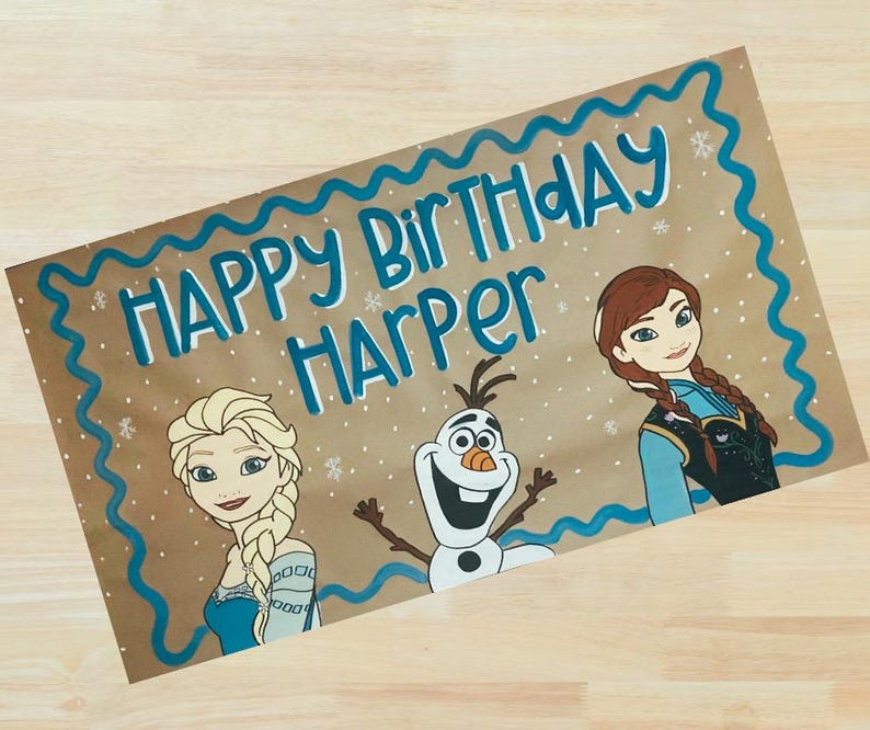 Op de afbeelding: Handgeschilderde verjaardagskaart op bruin papier met de woorden "Happy Birthday Harper" in blauw. De kaart bevat illustraties van Elsa, Anna en Olaf uit de film Frozen, met een blauwe golvende rand.