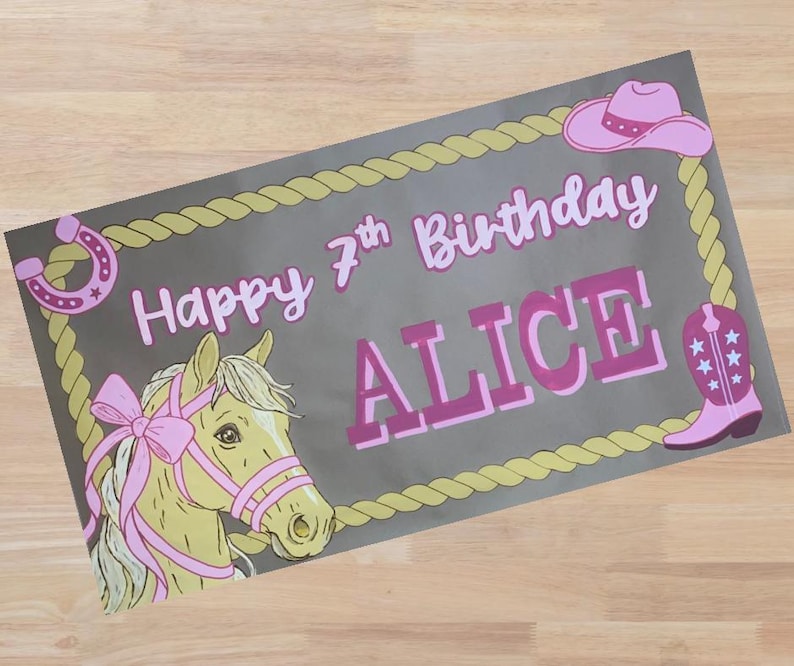 Op de afbeelding: Rechthoekige banner met een grijze achtergrond, met een paardenkop, hoefijzer, cowboyhoed en laars. De banner leest "Happy 7th Birthday ALICE" in roze letters, omlijst door een touwrand.