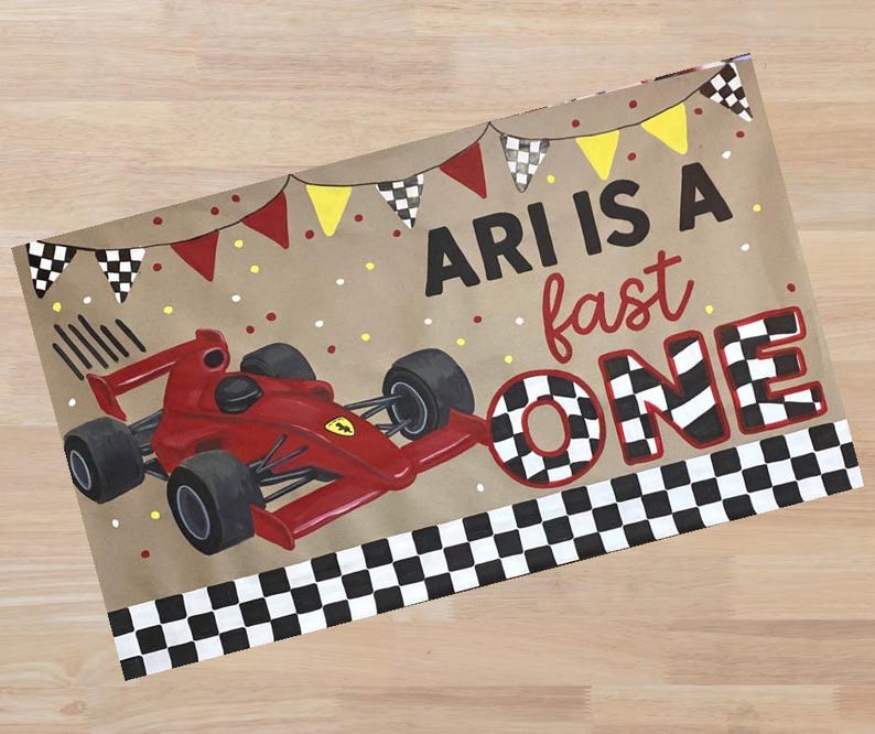 Op de afbeelding: Een bruine papieren feestzak met een rode raceauto-illustratie. De tas heeft de tekst "ARI IS A fast ONE" met geblokte vlag- en banneraccenten. De raceauto is rood met zwarte banden.