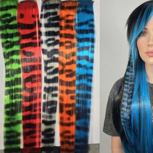 May include: A collection of colorful hair extensions in various patterns, including tiger stripes in green, red, white, orange, and blue. Two women are shown with blue and green hair extensions.