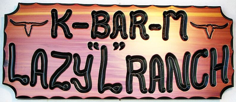 May include: A wooden sign with a pink and orange gradient background. The sign has black lettering that reads "K-BAR-M LAZY L RANCH". There are two stylized steer heads on either side of the sign.
