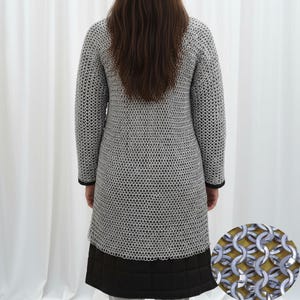 May include: A silver chainmail coat with long sleeves and a knee-length hem. The coat has a black trim at the cuffs and hem. The lower portion of the coat is black and quilted. The image shows the back of the coat.