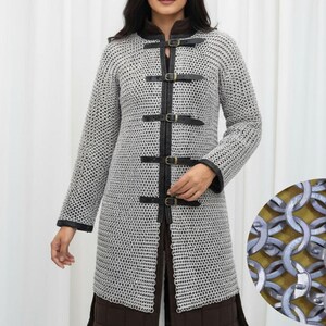 May include: A silver chainmail coat with black leather accents and buckles. The long-sleeved coat has a high collar and is fastened with leather straps. A close-up shows the interlocking metal rings.
