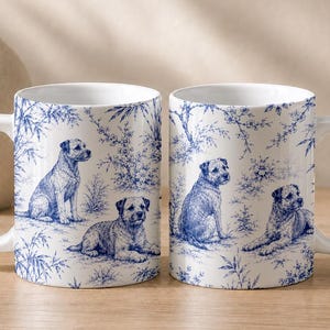 May include: Two white ceramic mugs featuring a blue toile-style pattern. The design displays detailed illustrations of dogs in various poses, including sitting and lying down, surrounded by intricate botanical elements like branches and leaves.