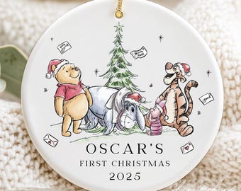 May include: White ceramic Christmas ornament featuring Winnie the Pooh, Eeyore, Piglet, and Tigger, all wearing Santa hats. The ornament has a gold string for hanging and includes the text "Oscar's First Christmas 2025".