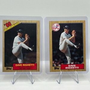 May include: Two Topps baseball cards featuring Dave Righetti of the New York Yankees in a pitching pose. The left card is labeled '86 Record Breaker' and the right card features the Yankees logo. Both cards are encased in clear plastic holders.