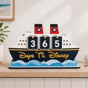 May include: A cruise ship countdown calendar featuring two red smokestacks with white Mickey Mouse icons. The dark blue hull displays the yellow text 'Days 'Til Disney' above light blue waves. Three black flip cards show the number 365.