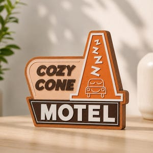May include: A wooden sign shaped like a traffic cone and motel sign with the text COZY CONE MOTEL. The sign features an orange cone with a sleeping car graphic and the letter Z repeated four times, set against a light tan and dark brown background.