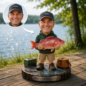 以下が含まれることがあります： FISHERMANと書かれた黒いキャップ、ダークグリーンのパーカー、カーキ色のショートパンツを着用し、大きな赤い魚を持つ人物のカスタムボブルヘッドフィギュア。台座は切り株の形をしており、DAD'S FISHING SPOTと刻まれたプレートが付いています。