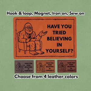 May include: Orange patch with a cartoon illustration of a Bigfoot character in a suit, seated and holding a notepad. Text reads "HAVE YOU TRIED BELIEVING IN YOURSELF?". Includes three smaller patches in different colors. The text "Choose from 4 leather colors" is also present.