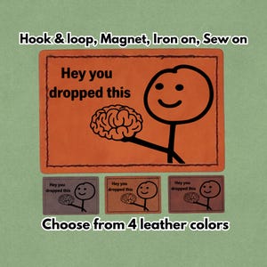 May include: Orange patch with the text "Hey you dropped this" and a stick figure holding a brain. Below are three smaller patches in different colors with the same design. The text "Choose from 4 leather colors" is at the bottom.