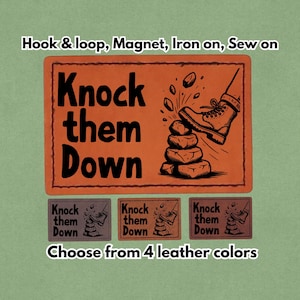 Może przedstawiać: Pomarańczowa prostokątna naszywka z napisem "Knock them Down" i ilustracją buta przewracającego stos kamieni. Poniżej znajdują się trzy mniejsze naszywki z tym samym wzorem. Widnieje również napis "Wybierz spośród 4 kolorów skóry". Naszywkę można przymocować za pomocą rzepu, magnesu, naprasowywania lub przyszywania.