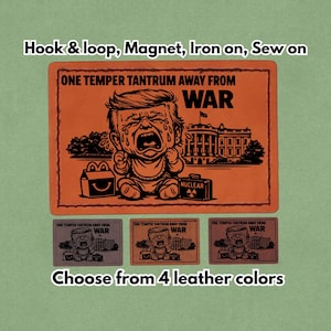 May include: An orange patch with the text "ONE TEMPER TANTRUM AWAY FROM WAR" and a cartoon of a crying baby. The image includes a White House illustration and a "NUCLEAR" suitcase. Available in 4 leather colours.