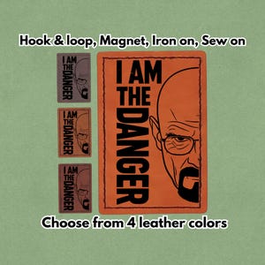 Pode incluir: Remendo retangular de couro laranja com o texto "I AM THE DANGER" e uma ilustração em preto e branco do rosto de um homem. Três remendos menores com o mesmo design são exibidos. O texto "Escolha entre 4 cores de couro" também está presente.