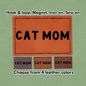 Könnte beinhalten: Ein orangefarbener Lederaufnäher mit dem Text "CAT MOM" in Schwarz. Das Bild zeigt auch drei kleinere Aufnäher mit dem gleichen Text in verschiedenen Farben. Der Text "Wählen Sie aus 4 Lederfarben" ist ebenfalls sichtbar.