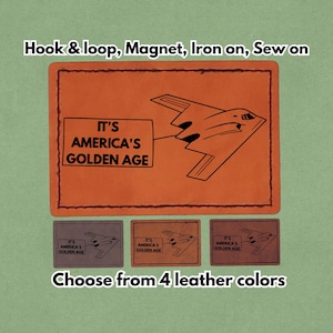 May include: Leather patch featuring a stealth bomber illustration and the text "IT'S AMERICA'S GOLDEN AGE." Available in four colours, with options for hook & loop, magnet, iron-on, or sew-on. The patch is orange.
