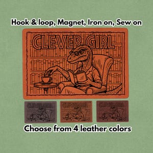 May include: An orange leather patch with the text "CLEVER GIRL" and an illustration of a dinosaur reading a book while seated in a chair. The patch is available in four leather colors and can be attached with hook and loop, magnet, iron-on, or sewn.