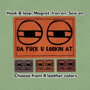 May include: Orange leather patch with the text "DA FUCK U LOOKIN AT" and two black eye designs. The patch is available in four leather colors and can be attached with hook & loop, magnet, iron-on, or sewn on.