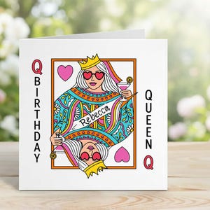 Op de afbeelding: Een witte wenskaart met een speelkaartontwerp. De kaart toont een koningin-illustratie met een hartvormige zonnebril en een kroon. De tekst luidt "BIRTHDAY QUEEN" en "Rebecca".