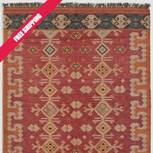 Handwoven wool and jute kilim rug in red with ivory geometric motifs and a blue-bordered border; fringed edges, 3x5 ft.