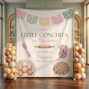 May include: A baby shower backdrop with the text "There's a Little Conchita in the oven". The design includes illustrations of a concha, a rolling pin, a baby onesie, and a plate of conchas. The banner is decorated with colorful papel picado.
