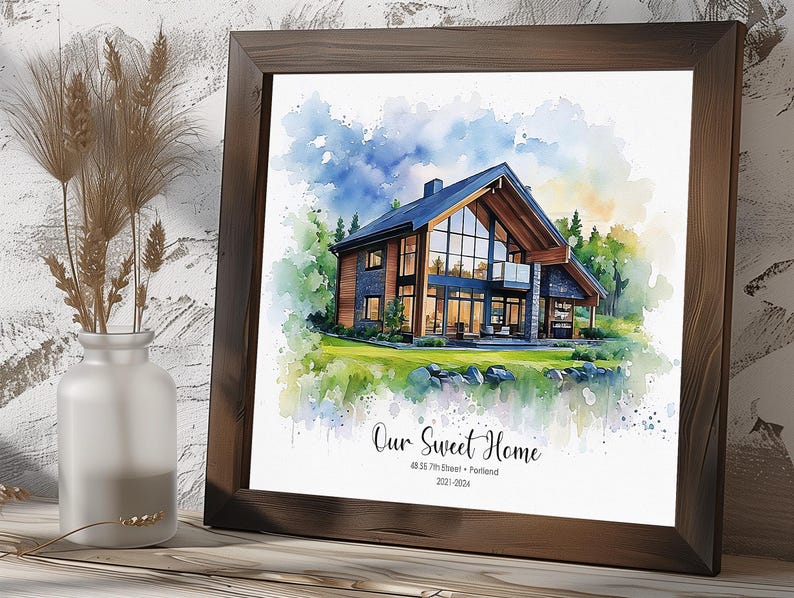 May include: Watercolor print of a modern house with a dark wood frame. The artwork features a house with large windows, surrounded by trees and a blue sky. Text reads "Our Sweet Home" and address.