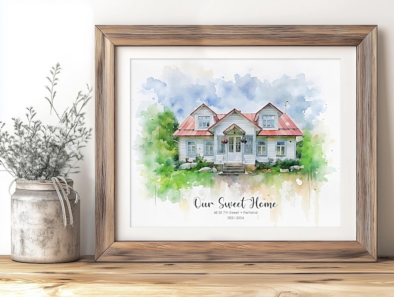 May include: Watercolor print of a white house with a red roof, framed in wood. The artwork features the text "Our Sweet Home" and the address "48 SE 7th Street &bull; Portland 2021-2024". The house is surrounded by green foliage and a blue sky.