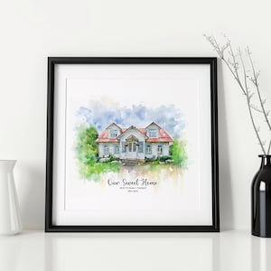 May include: A framed watercolor print of a house with a red roof, white siding, and green landscaping. The print is in a black frame and includes the text "Our Sweet Home" and an address. A white vase and a black vase with branches are on either side.