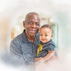 May include: A smiling older man holds a baby in a black t-shirt with a yellow design. The man wears a gray striped polo shirt. The background is a soft, blurred watercolor effect, creating a warm and gentle atmosphere.