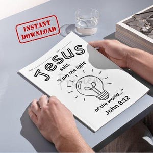 以下が含まれることがあります： 「イエスは言われた、『わたしは世の光である…ヨハネ8:12』」という言葉と電球のイラストが描かれた白い塗り絵のページ。 「インスタントダウンロード」という言葉が赤いスタンプで表示されています。 テーブルには水の入ったグラスがあります。