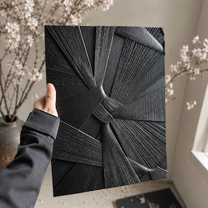 May include: A rectangular black wall art piece featuring a textured surface with raised, radiating lines that converge and overlap in a geometric pattern. The design consists of multiple segments of thin, parallel grooves creating a sunburst effect.