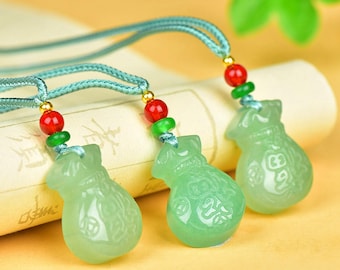 May include: Three jade-green money bag pendants with intricate carvings, strung on light blue cords. Each pendant is accented with red and green beads. The background is a scroll and a soft yellow surface.